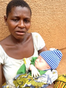 Photo of a mother holding her infant child at Kabanga, forced to leave her village after the birth of her child